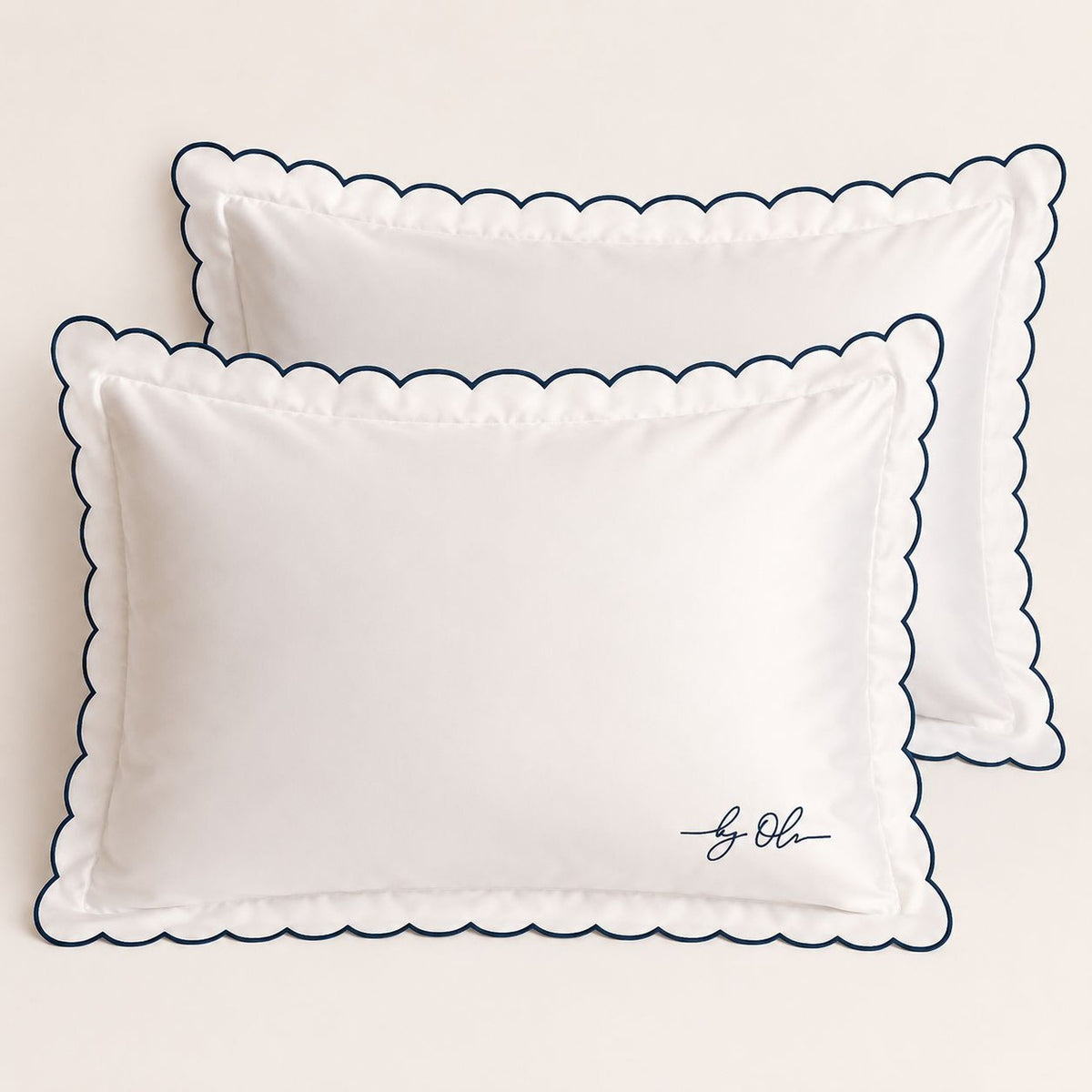 Two white pillows with scalloped edges on a beige background
