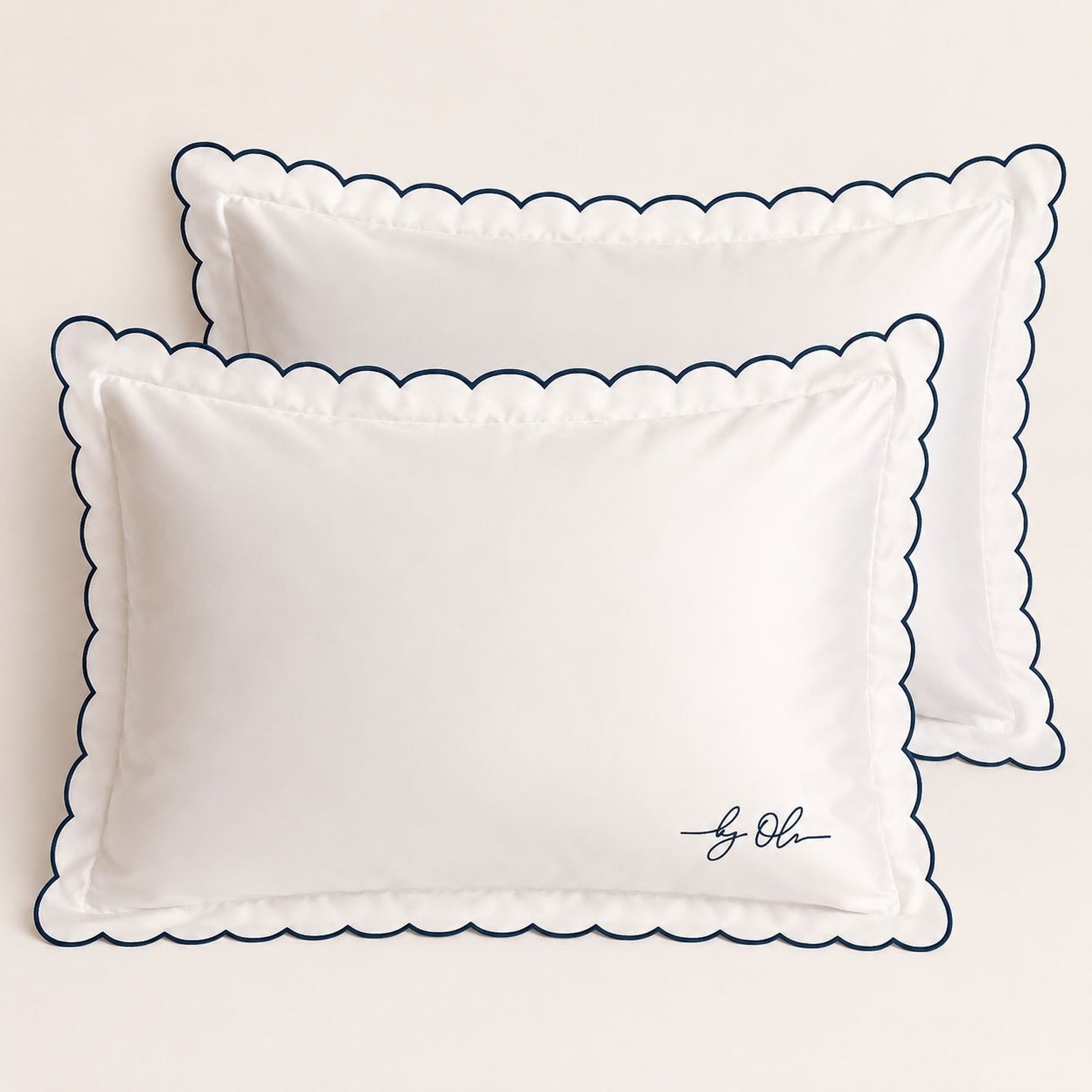 Two white pillows with scalloped edges on a beige background