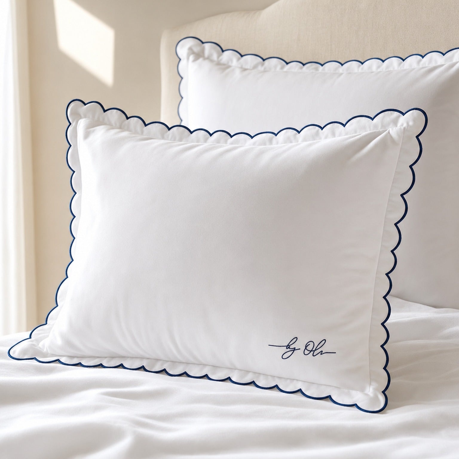 White pillows with blue scalloped edges on a bed