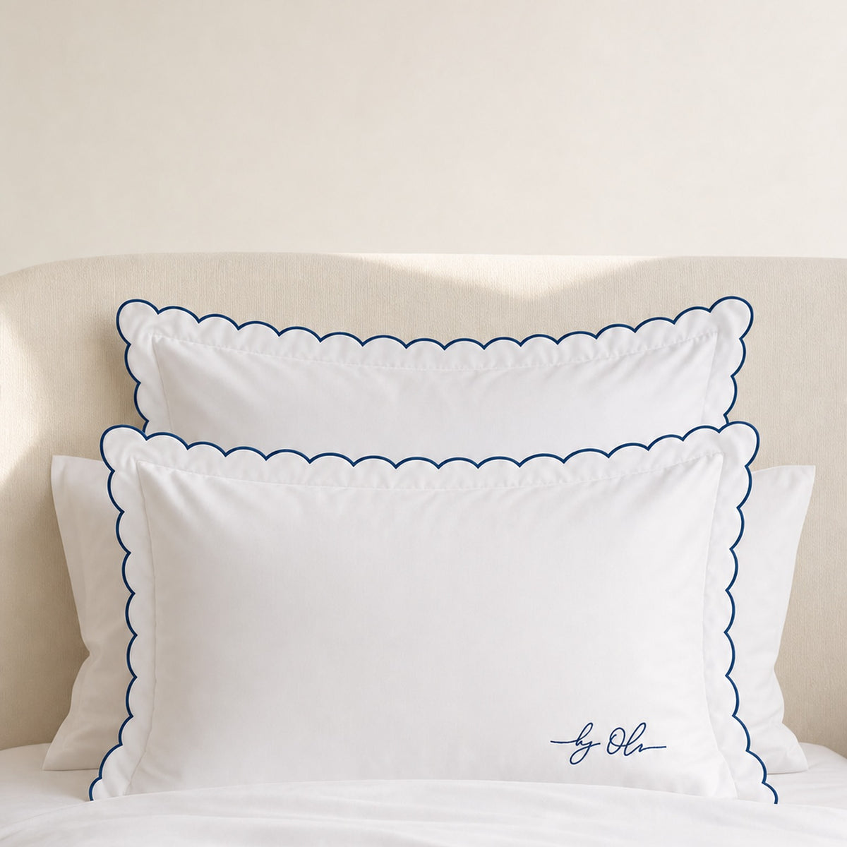 White pillows with blue scalloped edges on a beige background