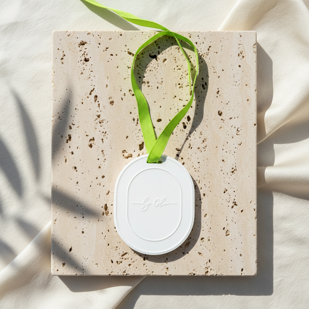 White oval product with green ribbon on a textured beige surface
